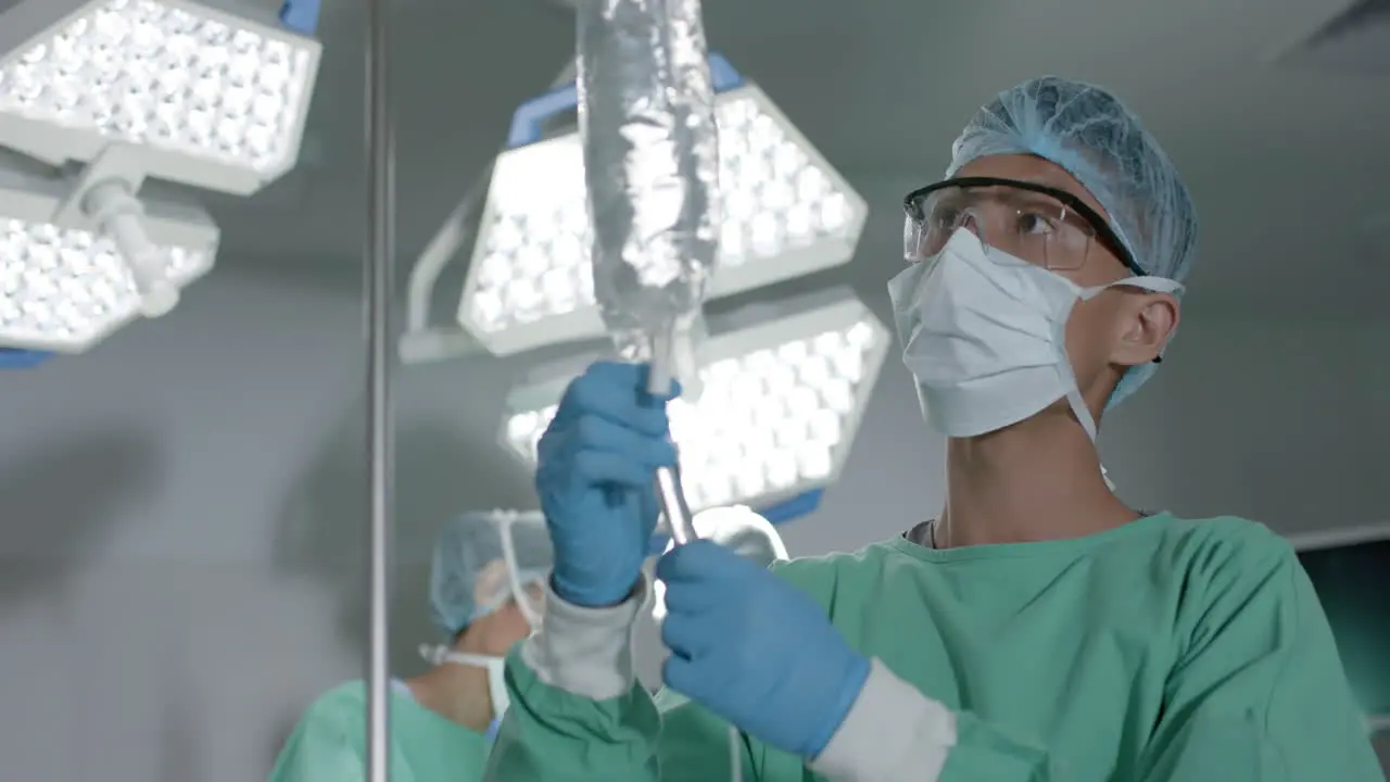 Young Asian man in medical scrubs prepares an IV bag in a hospital