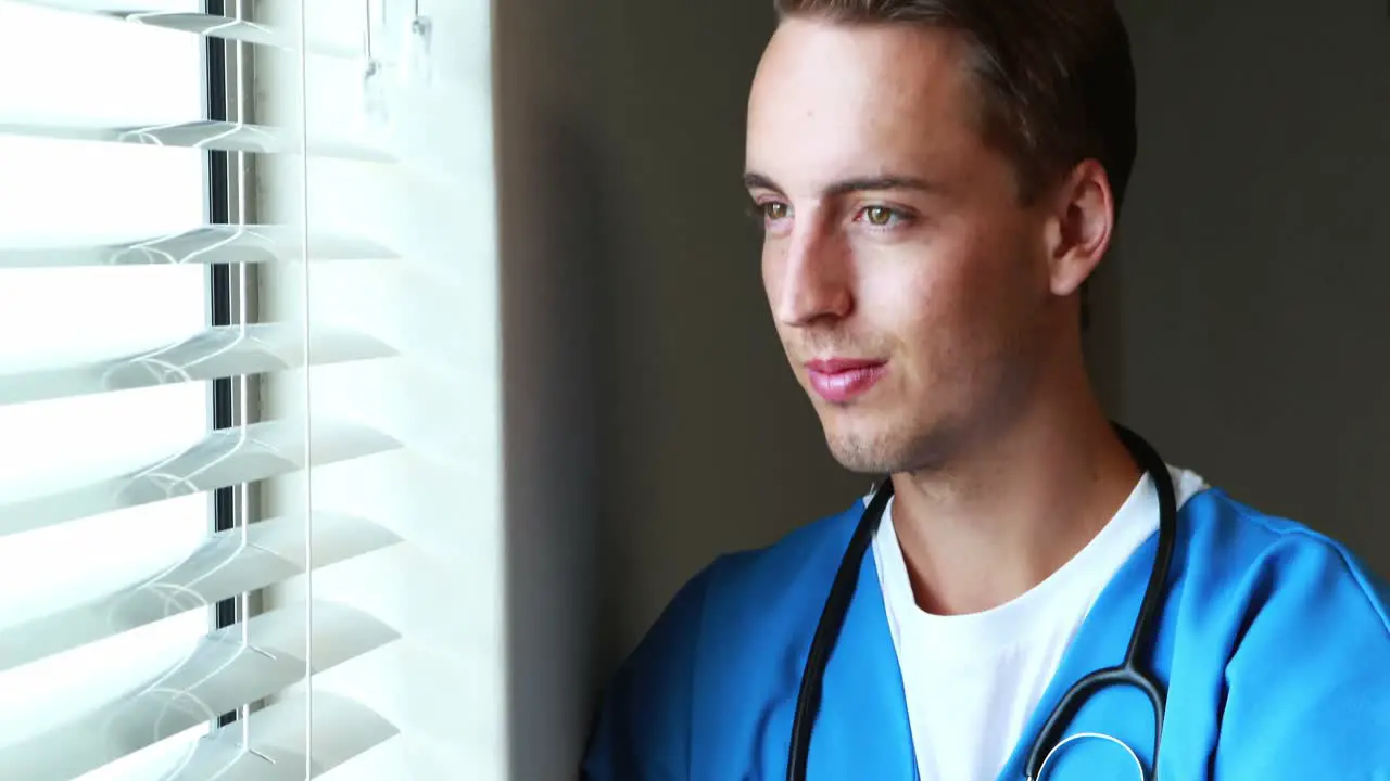 Doctor standing with arms crossed and looking through window