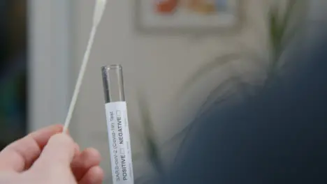 Over the Shoulder Shot of Person Placing a Used Swab In Test Tube During Home COVID Self Test