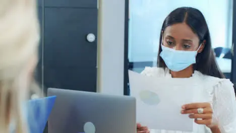 Over the Shoulder of Woman In Face Mask Looking at Document 