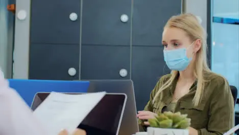 Over the Shoulder Pan of Woman In Face Mask On Laptop