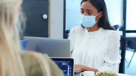 Over the Shoulder of Woman In Face Mask Looking at Laptop