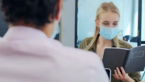 Over the Shoulder Pan of 3 Colleagues In Face Masks Working