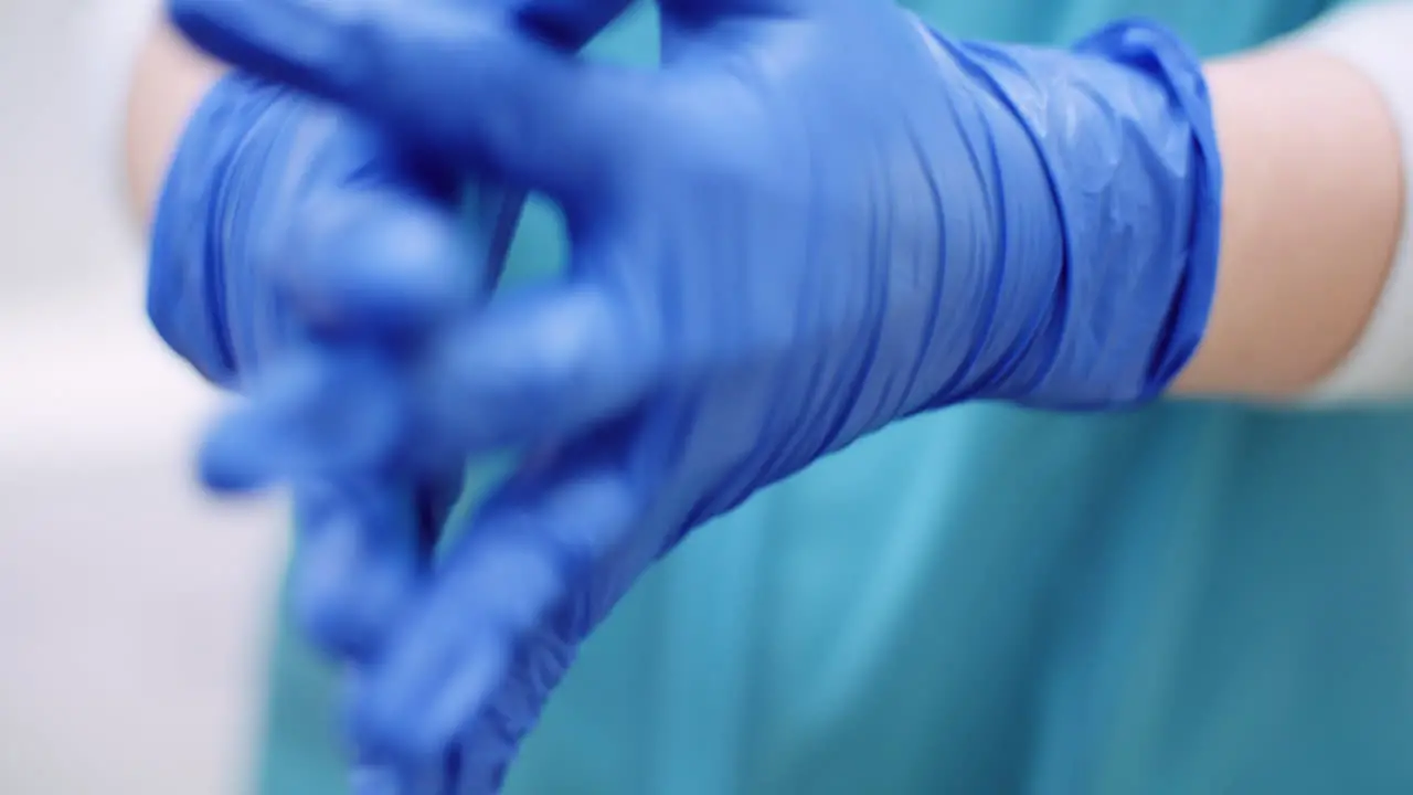 Female Surgeon Putting On Protective Gloves