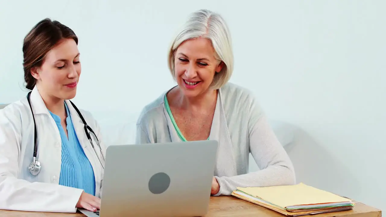 Female doctor interacting with a patient while using laptop