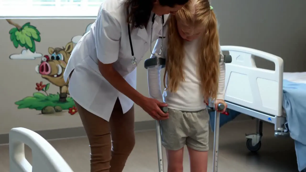 Female doctor assisting girl to walk with crutches