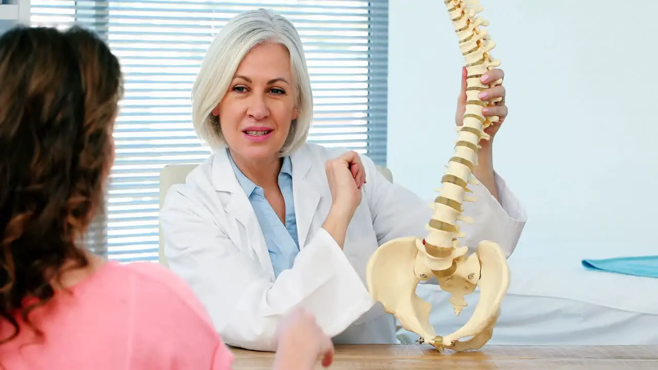 Female doctor explaining spine model to female patient