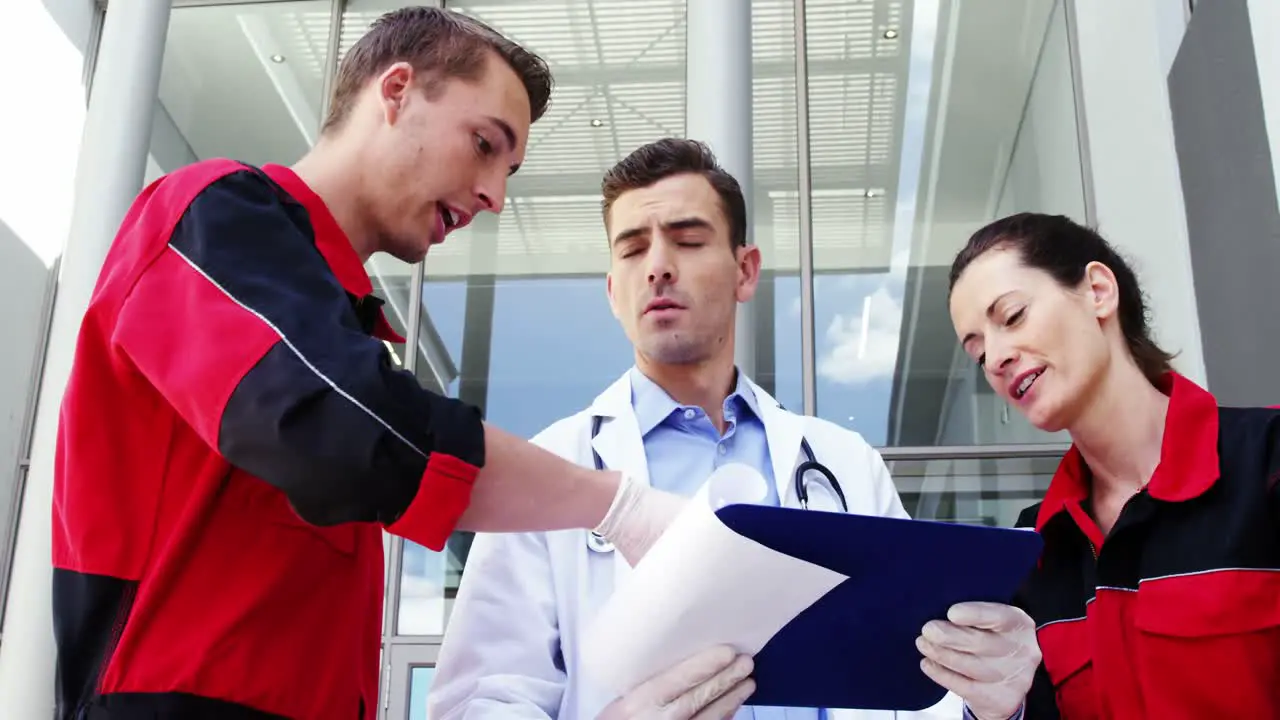 Paramedics and doctor discussing over medical report