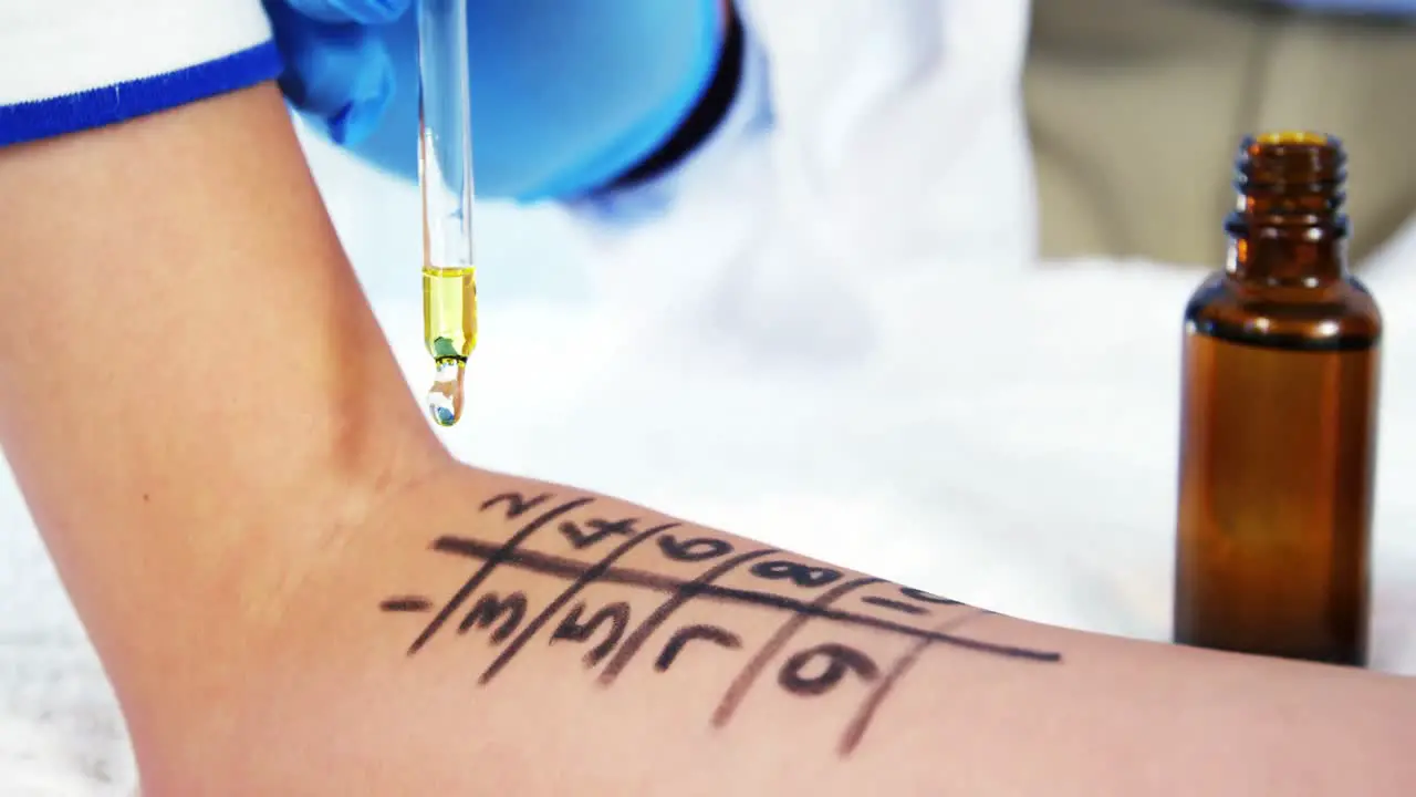 Doctor holding medicine dropper over a hand of patient with number grid