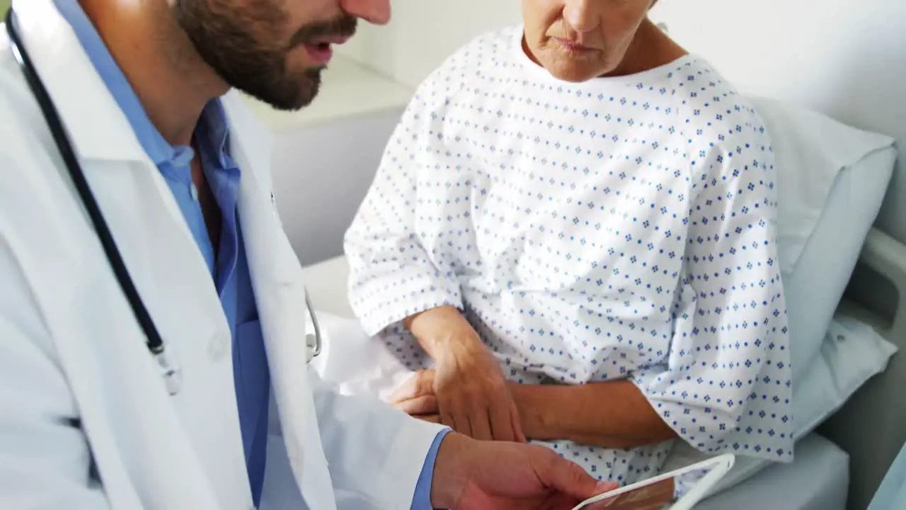 Male doctor discussing medical report with female patient on digital tablet