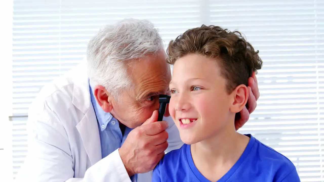 Male doctor examining a patients ear with horoscope