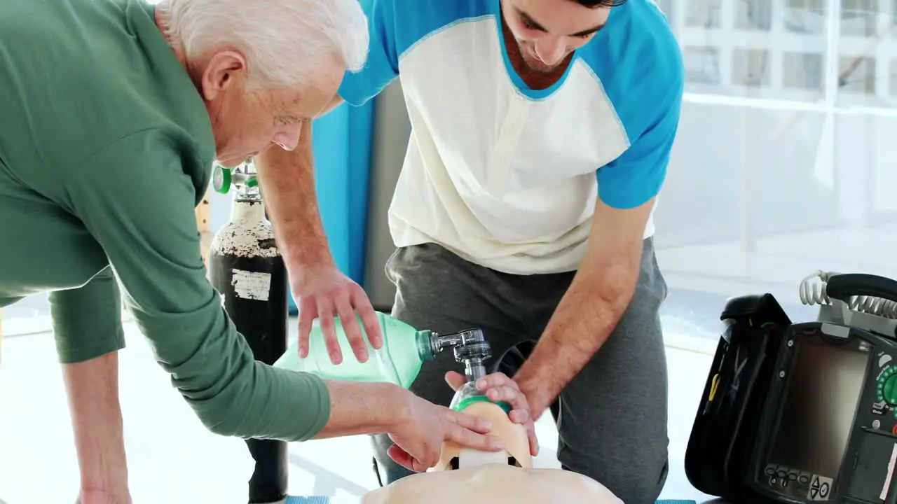 Two male paramedics giving oxygen to a dummy