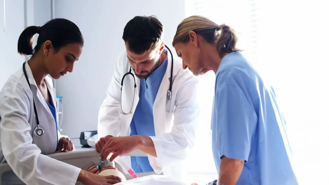 Team of doctors putting oxygen mask on a female senior patient face