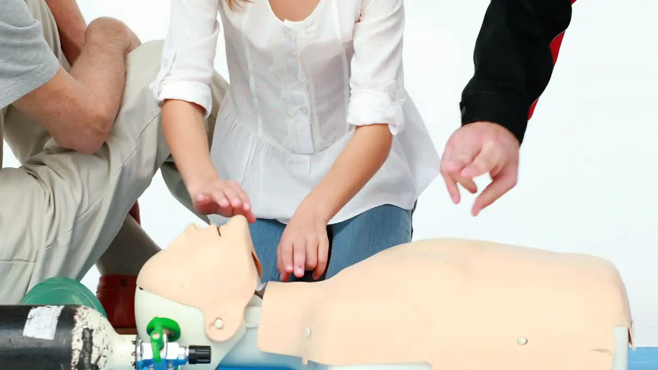 Two male paramedics giving a demo on a dummy with a girl child