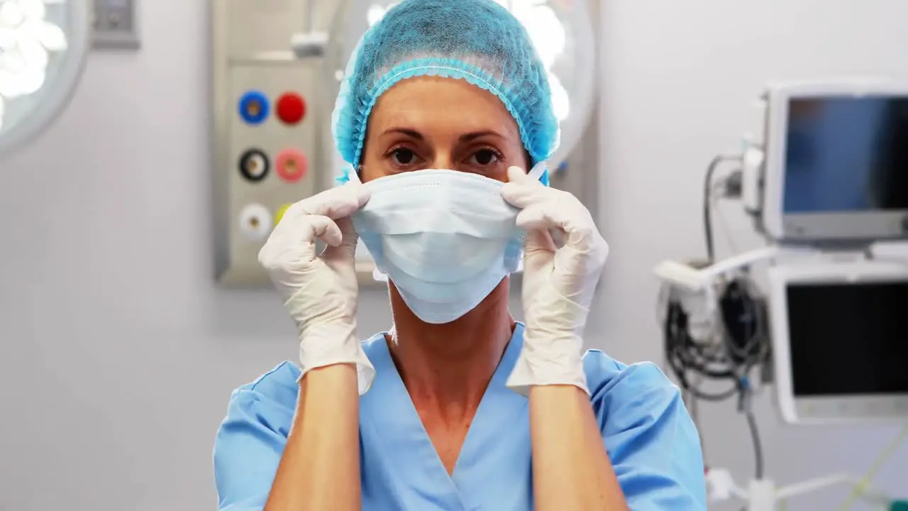 Female nurse tying surgical mask in operation theater