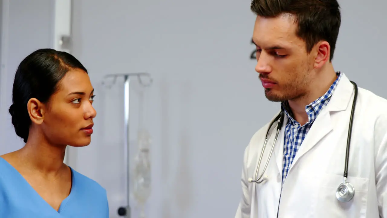 Nurse and doctor discussing over clipboard