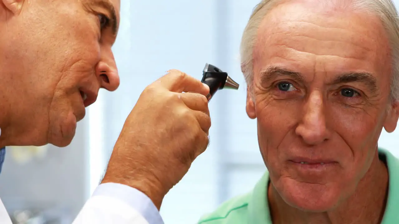 Doctor examining patients ear with otoscope