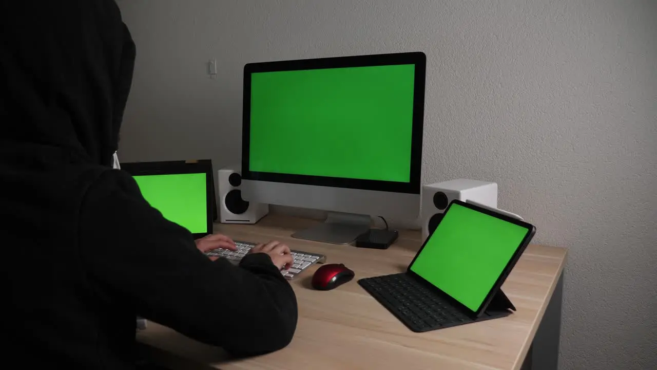 Shady hacker in a hoodie on multiple screens