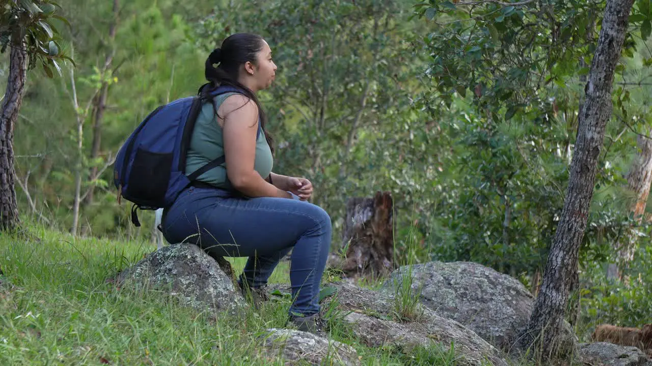 Photographer woman carrying a backpack and her camera plays with a white dog in the forest