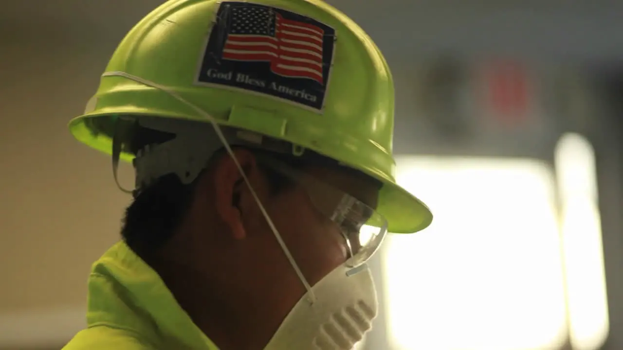 An American factory worker wears a helmet with a flag