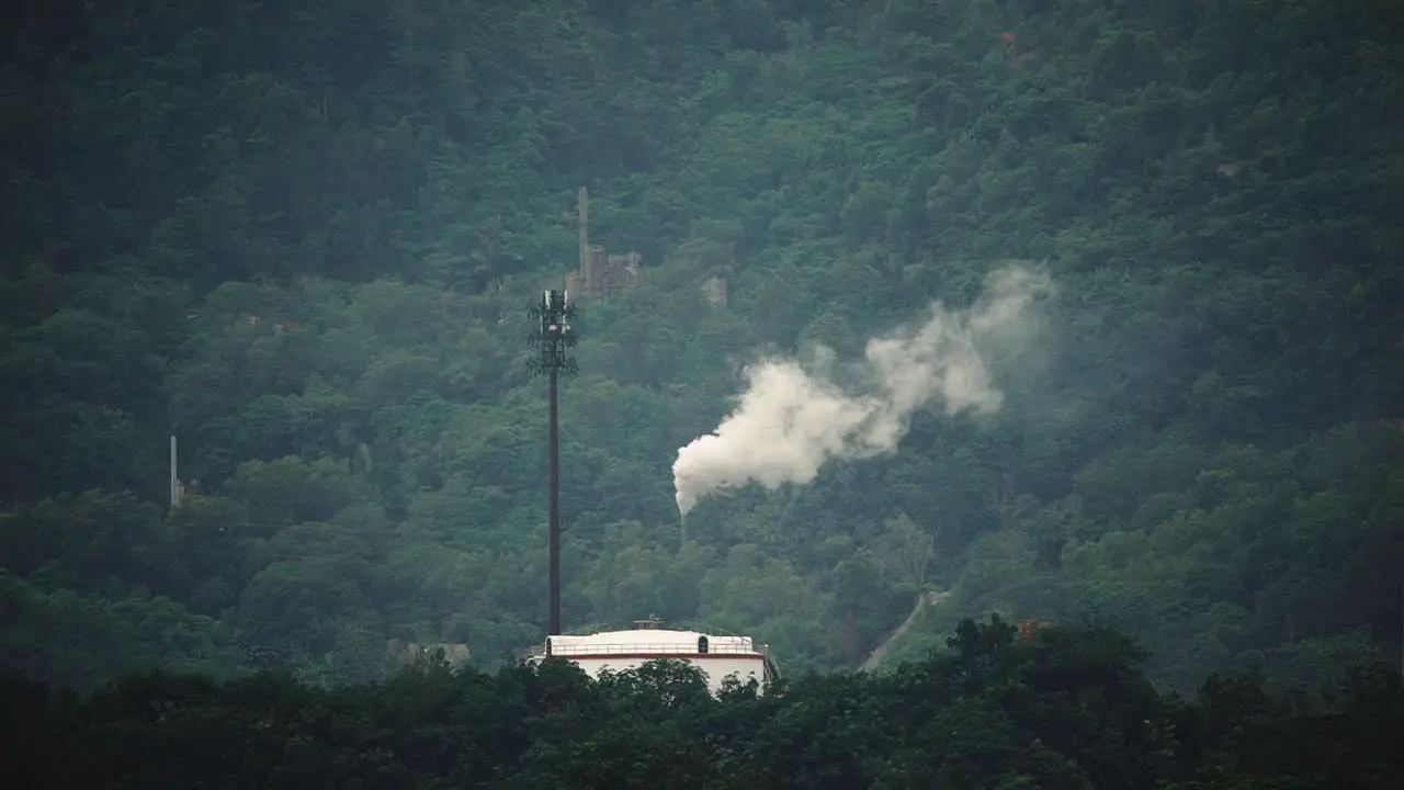 A factory near a mountain range_produce a white smoke_wide shot_long shot_50fps