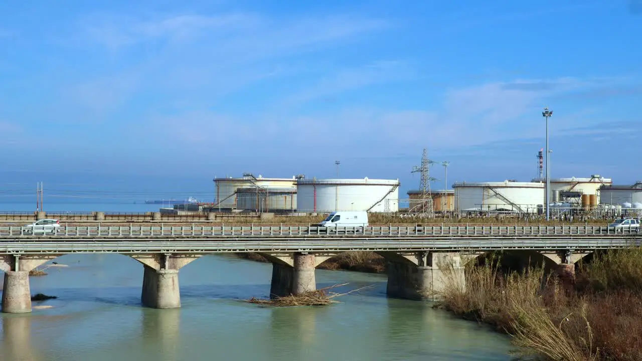 traffic on the bridge in front of a fuel refinery near the sea real time shot pollution concept