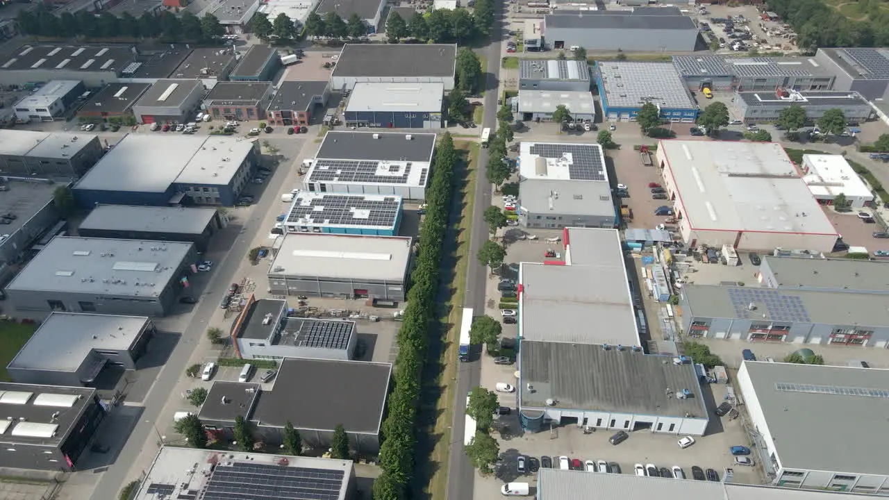 Aerial of truck driving over busy industrial terrain with multiple buildings with solar panels on rooftops