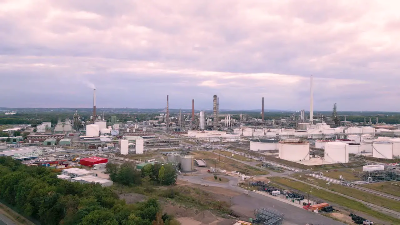 Aerial drone fly away from an chemical industry plant in Sürth Cologne Germany plant producing fuel gas for transportation with chimneys and cloudy sky bird view helicopter flight summer 2022