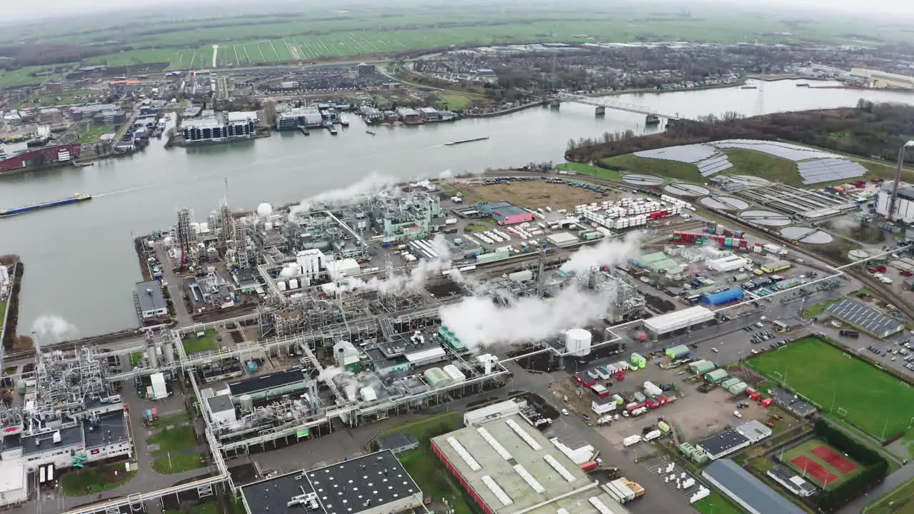 Riverside urban industrial area with factory chimney smoke stadium and streets