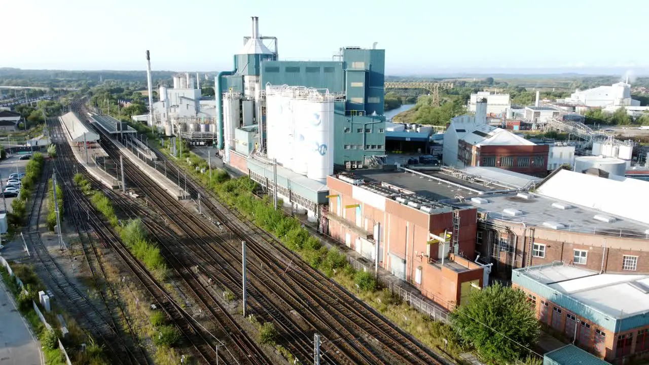 Industrial chemical manufacturing factory next to Warrington Bank Quay train tracks aerial view low to high