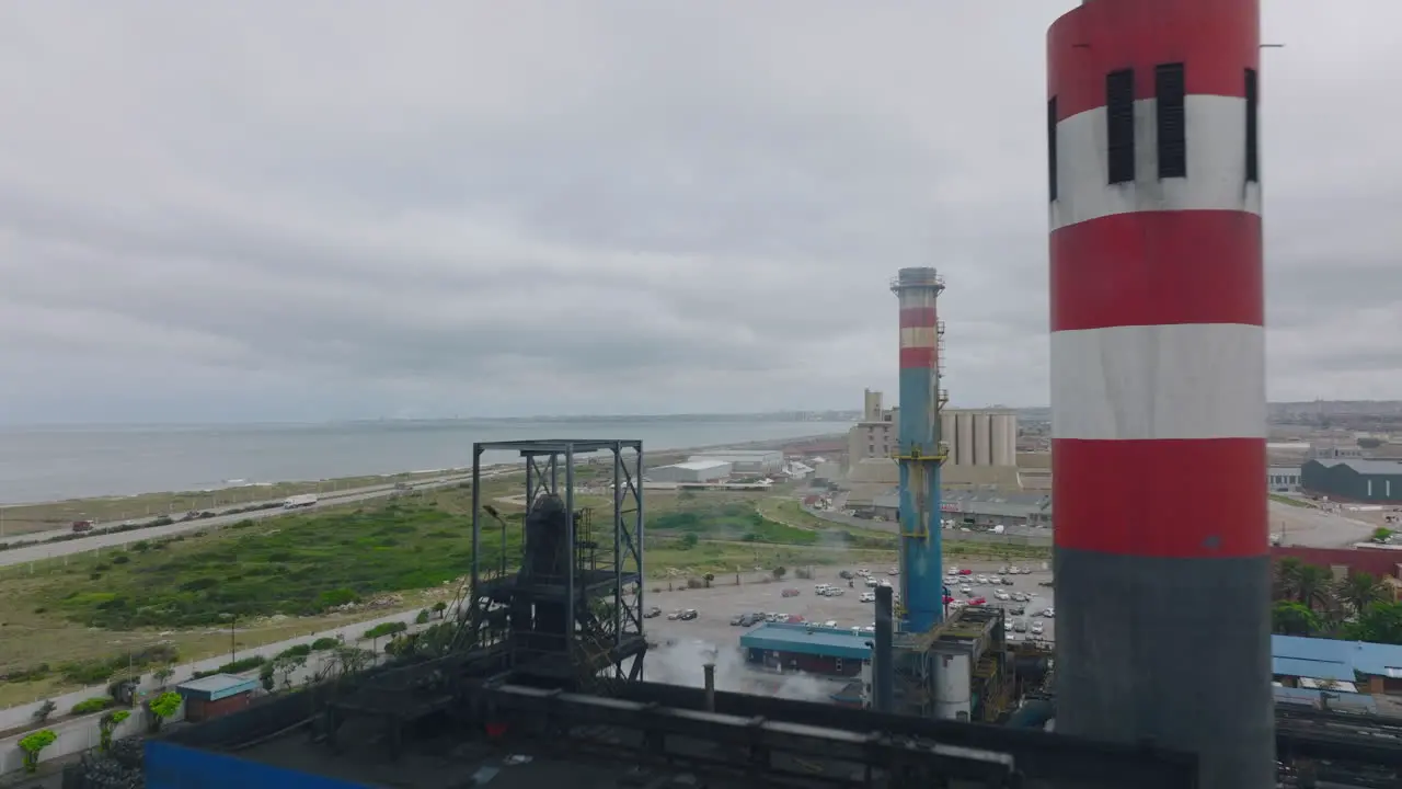 Forwards fly over production plant Revealing car park and highway leading along sea coast Port Elisabeth South Africa