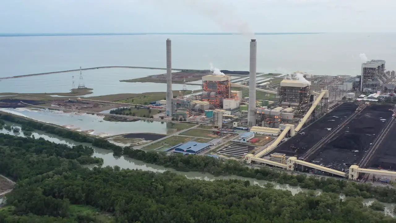 Aerial shot of coastal coalfield industrial ultra-supercritical coal-fired power plant with smokes raising from chimney located at lekir bulk terminal jalan teluk rubiah manjung perak malaysia