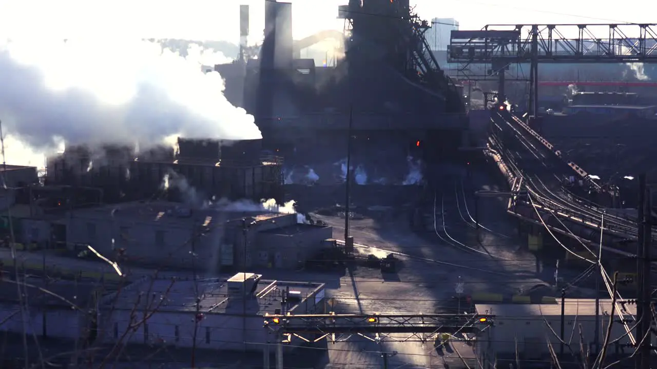 Establishing shot of a busy steel mill with smoke belching suggests global warming 2