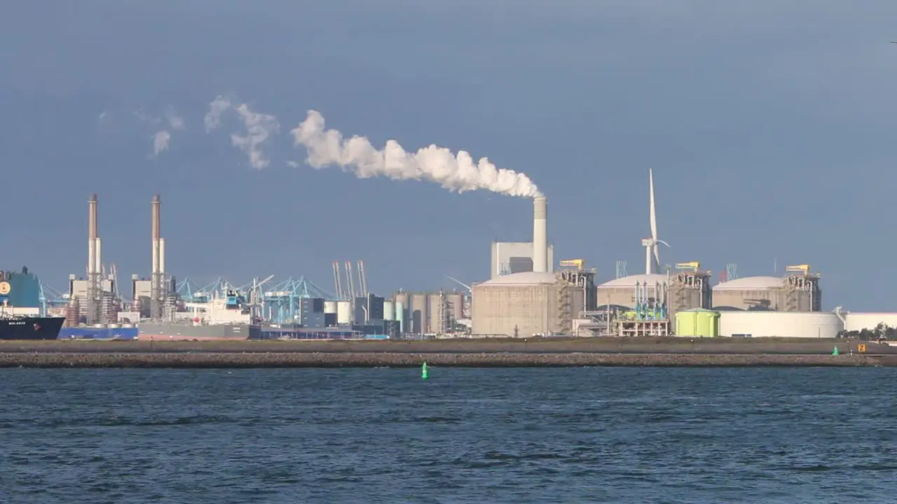 Dock with factories and chimney emitting steam or smoke