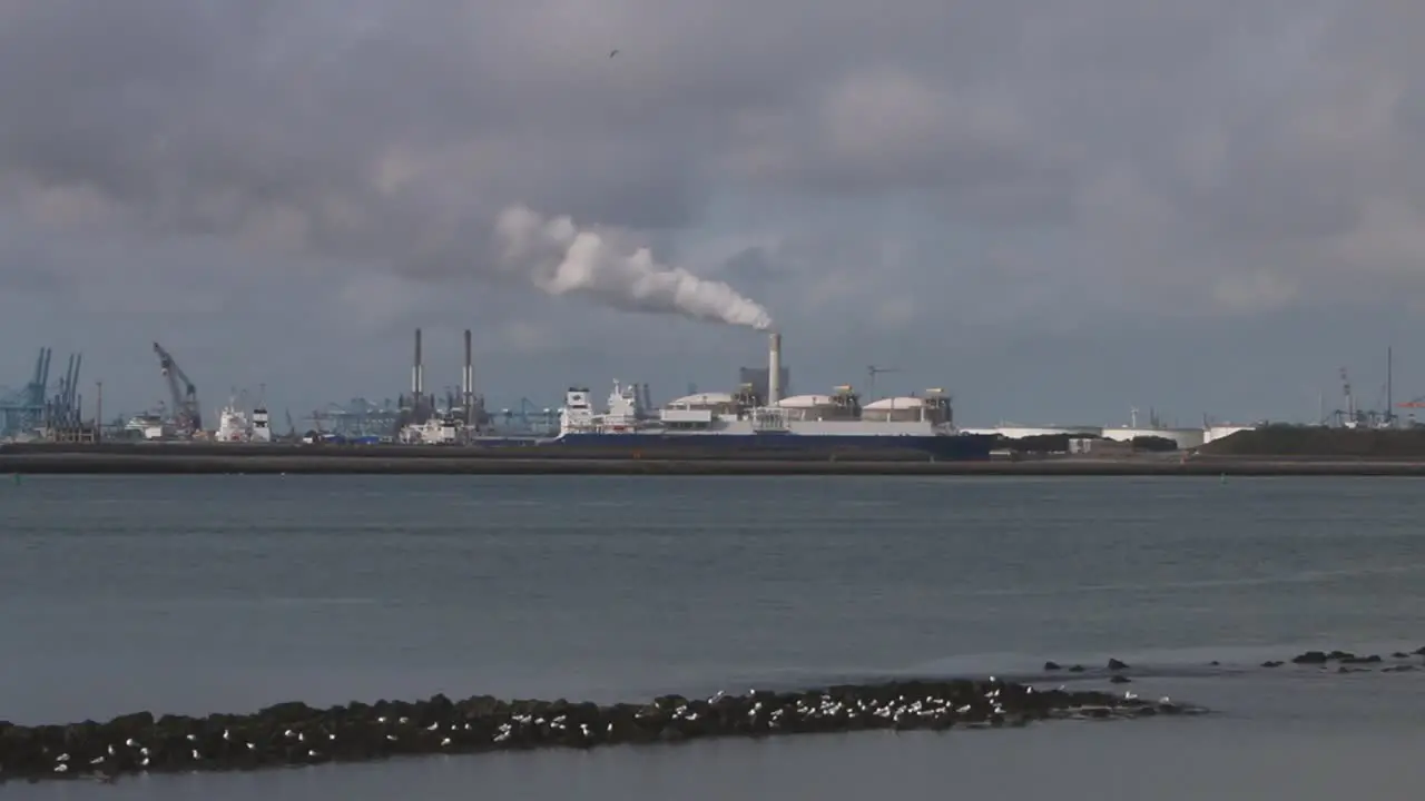 Looking across the water from the Hook of Holland towards factories chimney docks etc