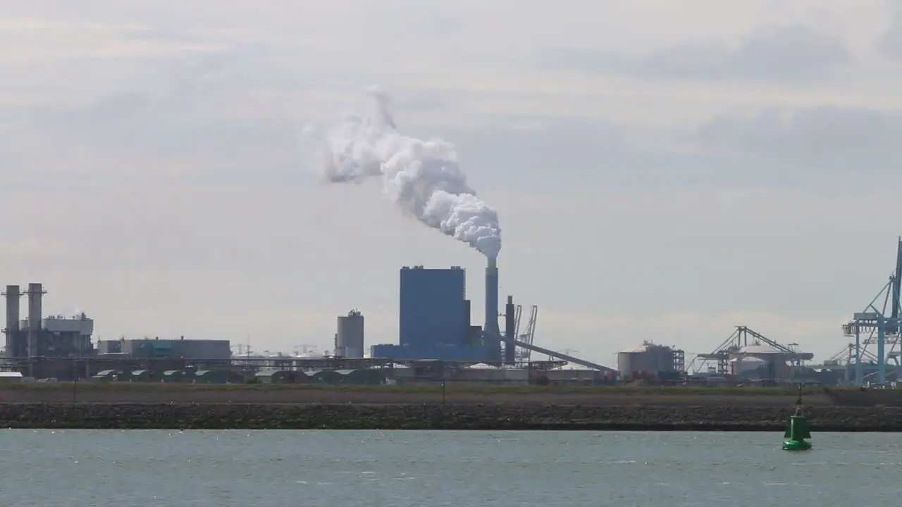 Looking across the water from the Hook of Holland towards factories chimney and docks etc-1