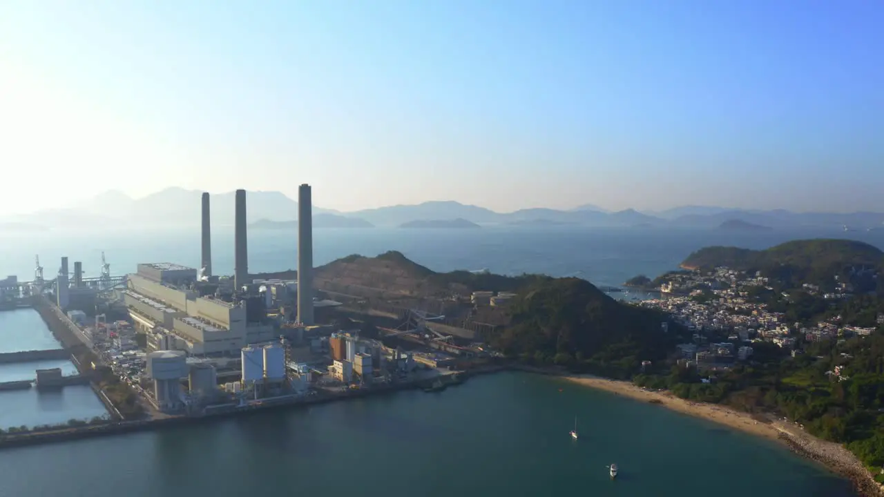 Drone shot of a big coastal coal-fired power plant on an island next to a village with a beach during a beautiful sunny day-1