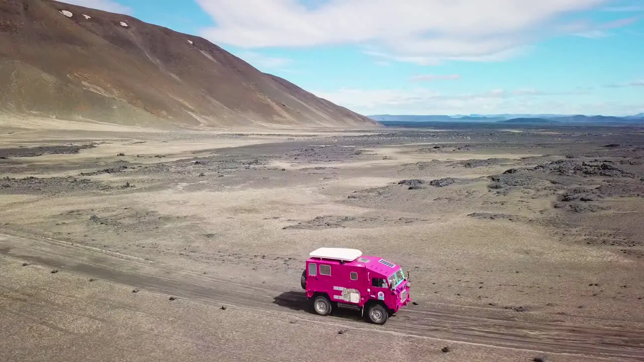 Aerial of a rare pink Land Rover 101 driving through the outback highlands of desolate Iceland 3