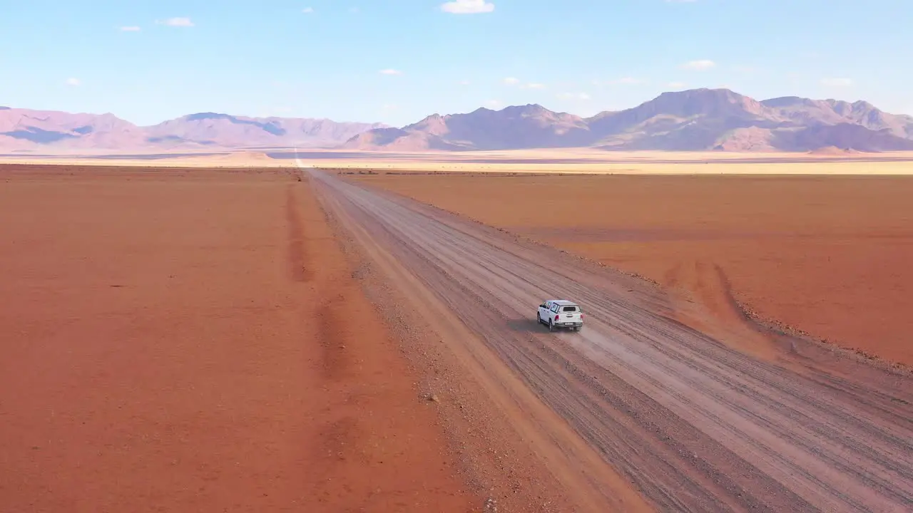 High aerial over a Toyota safari vehicle heading across the flat barren Namib Desert in Namibia 2