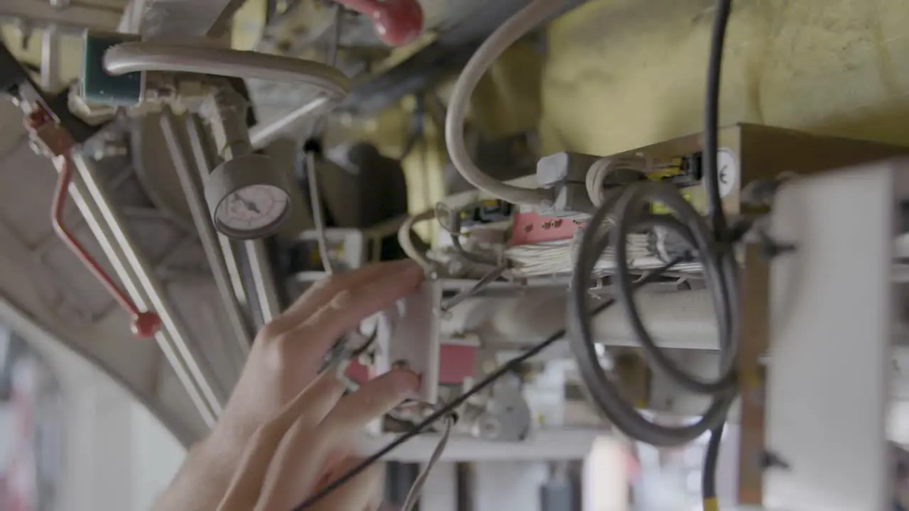 Close-up of two hands expertly connecting wires and cables in a documentary-style handheld shot foreground in focus