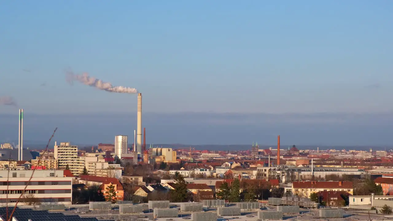 Skyline of industrial part of a city with chimney of power plant producing smoke