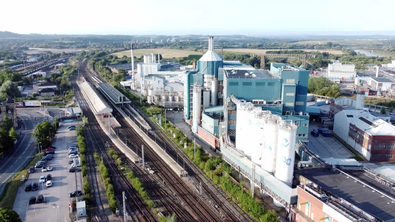 Industrial chemical manufacturing factory next to Warrington Bank Quay train tracks aerial view rising shot