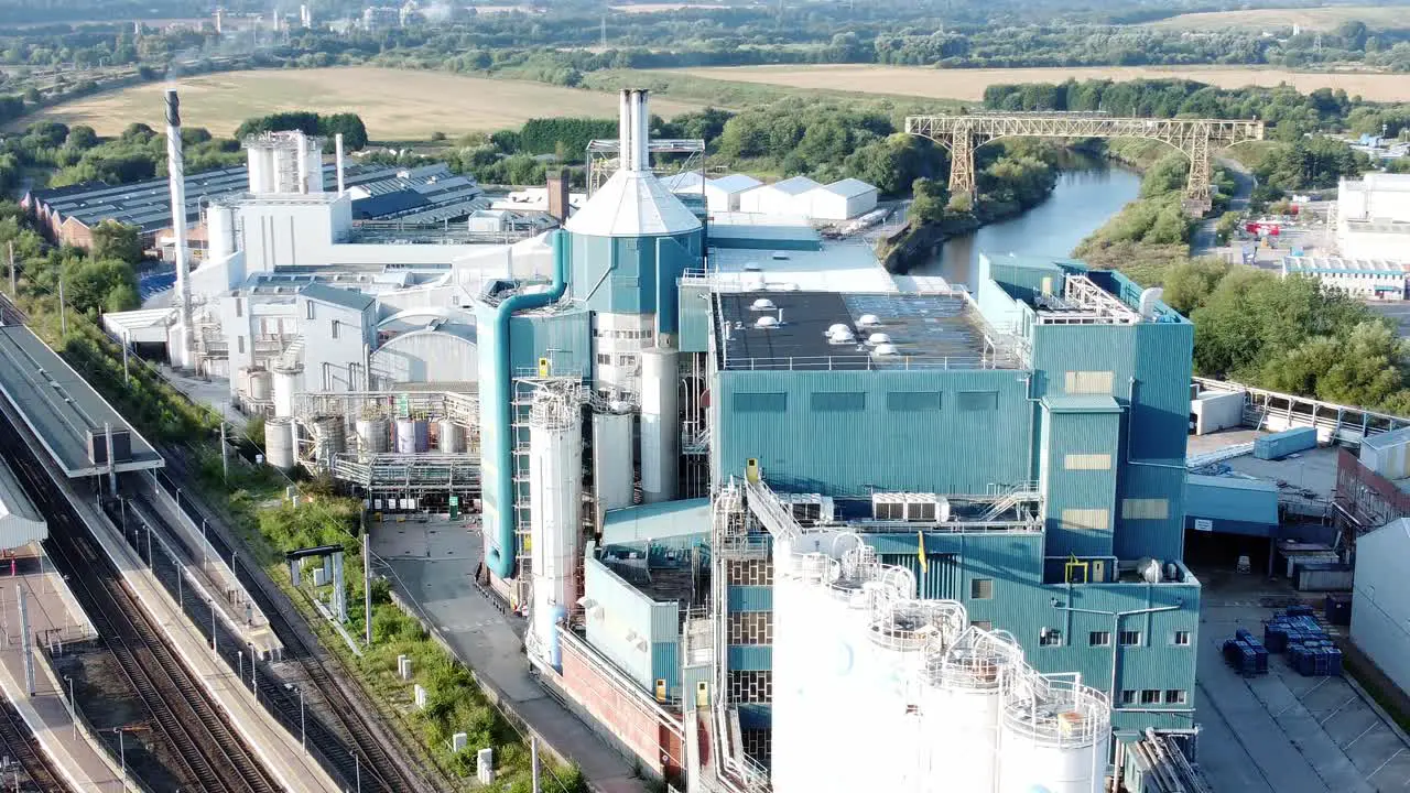 Industrial chemical manufacturing factory next to Warrington Bank Quay train tracks aerial view right orbit shot