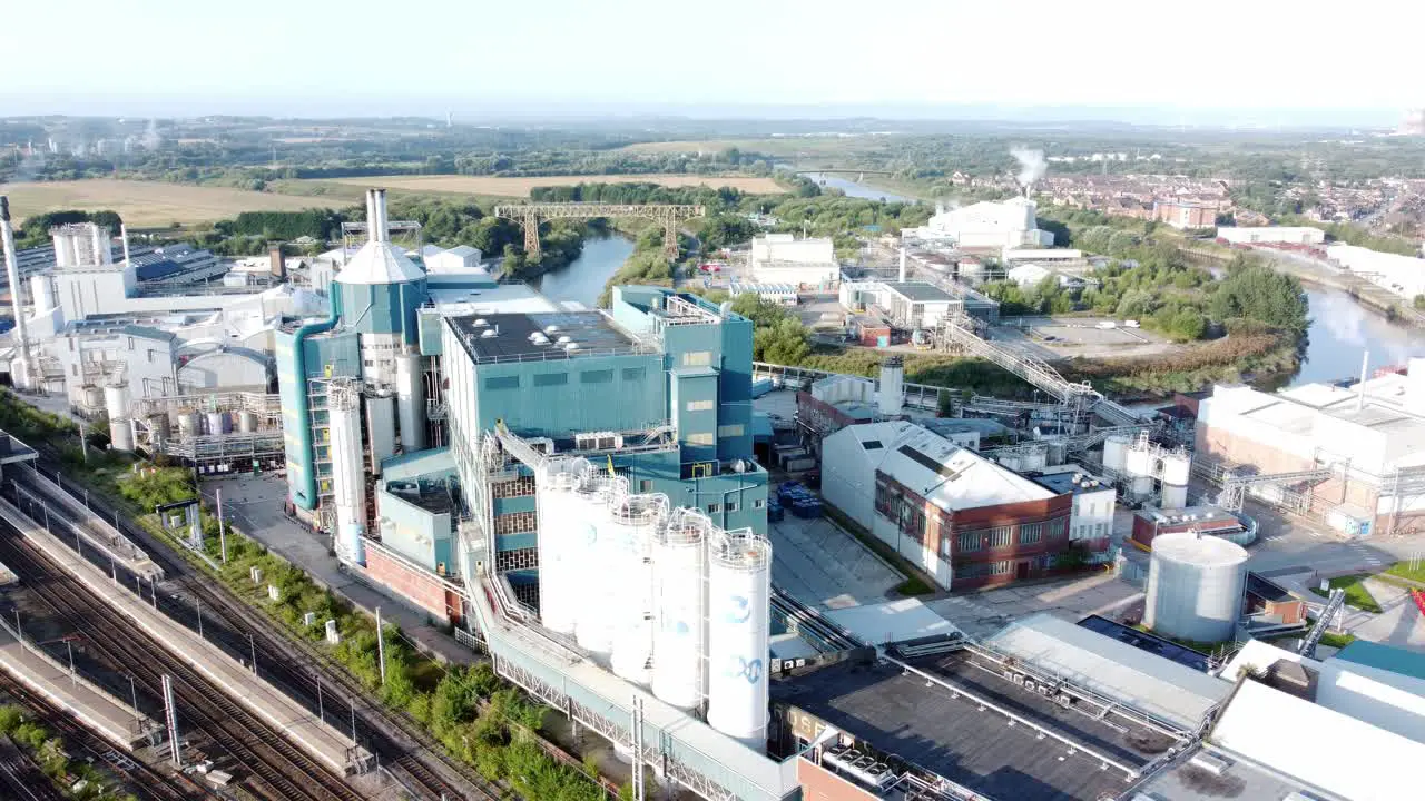 Industrial chemical manufacturing factory next to Warrington Bank Quay train tracks aerial view dolly left