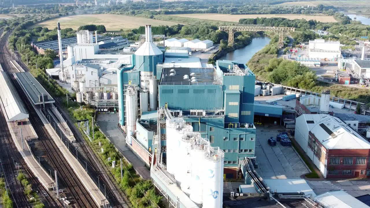 Industrial chemical manufacturing factory next to Warrington Bank Quay train tracks aerial descending view