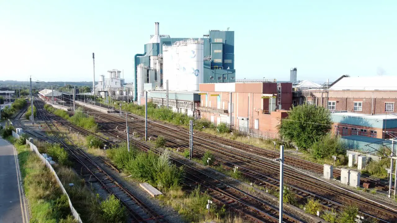 Industrial chemical manufacturing factory next to Warrington Bank Quay train tracks rising aerial view