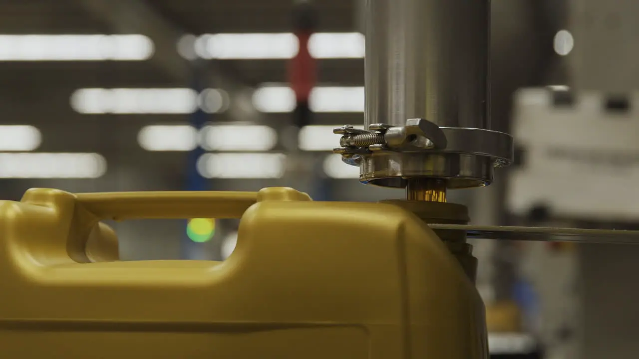 A machine depositing oil into a golden plastic jug