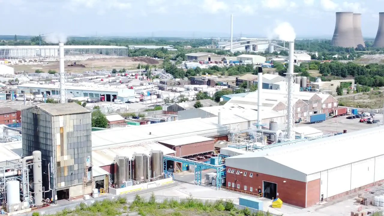 Industrial warehouse power plant refinery buildings under smokestack wasteland aerial view push in right