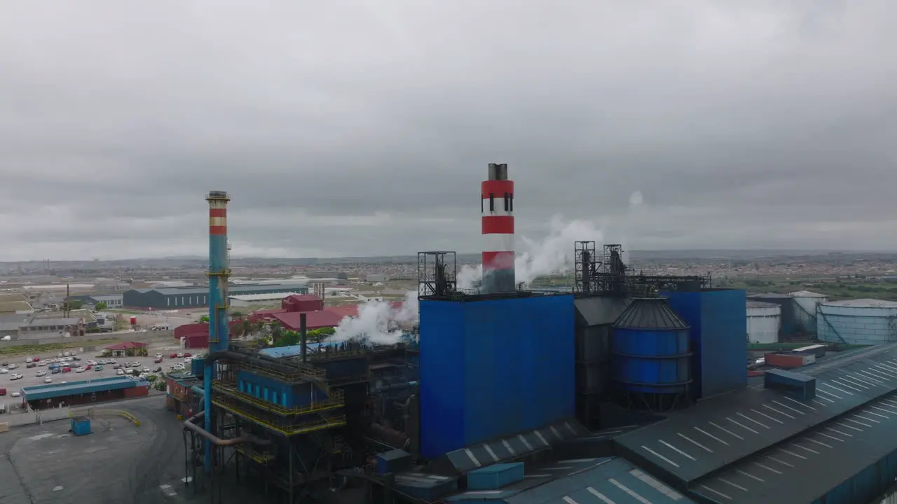 Fly around factory Industrial buildings with chimneys and emitted steam or smoke Port Elisabeth South Africa