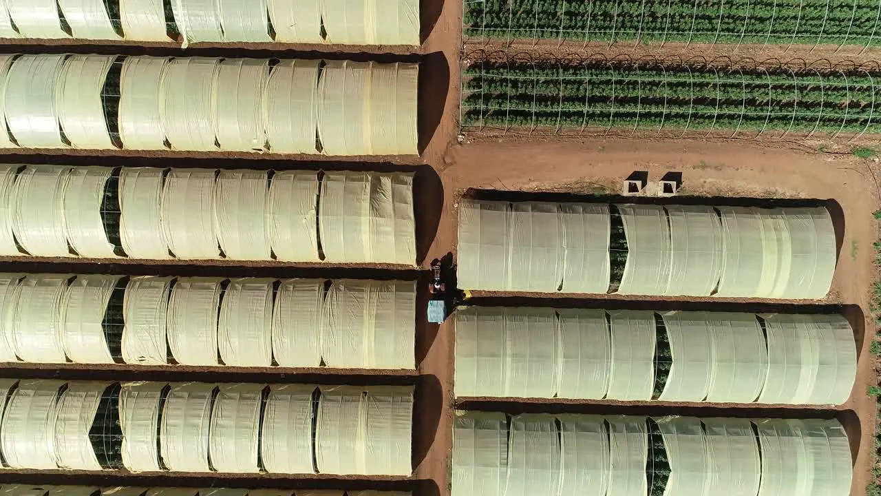 Aerial bottom up view of greenhouse with a tractor going through it